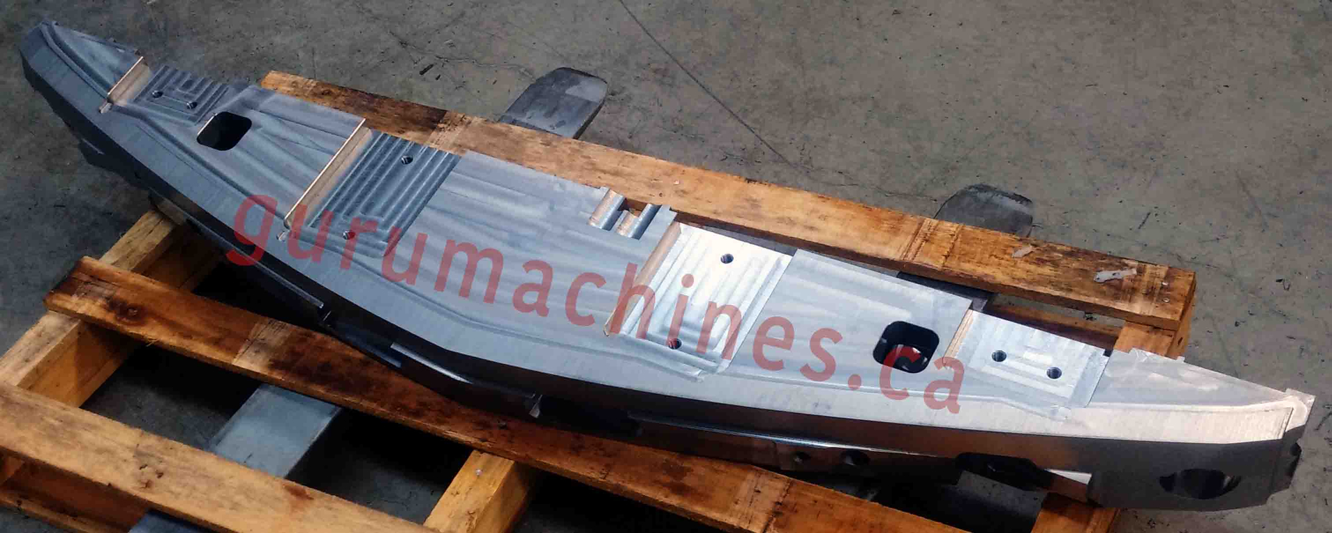 Long curved machined aluminum beam resting on a pallet