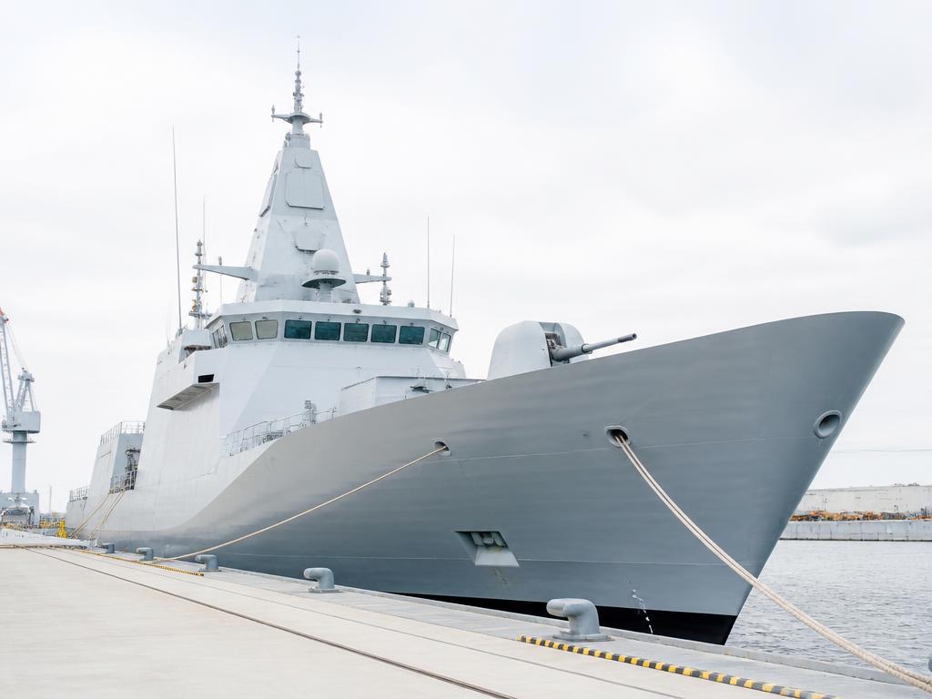 Naval patrol vessel moored at a bright dockside